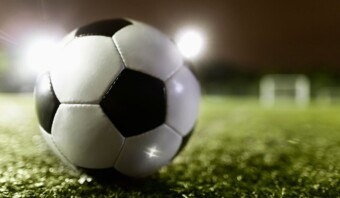 Un balón de fútbol descansa sobre un campo de césped por la noche durante el mundial femenino.