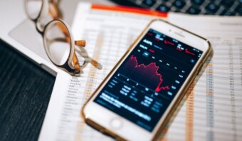 Un teléfono inteligente muestra un gráfico de acciones de comercio electrónico en un escritorio.
