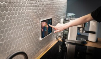 Una persona señalando sus dispositivos inteligentes un ipad en la encimera de la cocina.