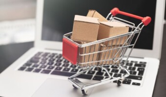 Un carro de la compra está sobre una computadora portátil en un minorista.