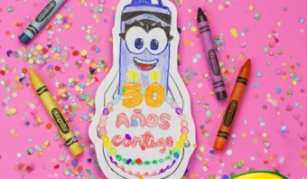 Un pastel de cumpleaños con crayones y crayones sobre un fondo rosa.