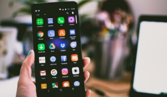 Una persona sosteniendo un teléfono inteligente con muchos íconos.