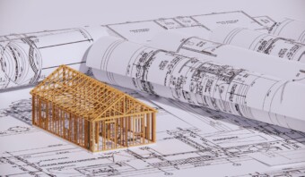 Un modelado 3D del marco de una casa sobre planos arquitectónicos.