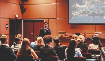 Un hombre habla en un podio en una sala de conferencias llena de atentos miembros de la audiencia en el evento EMMS E-commerce 2024.