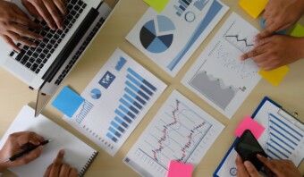 Equipo analizando datos y gráficos durante una reunión de negocios sobre IA en investigación de mercados.
