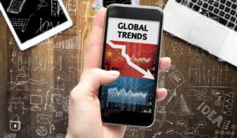Una mano sosteniendo un teléfono inteligente que muestra "tendencia digital" con gráficos, sobre un fondo de garabatos de negocios dibujados a mano.