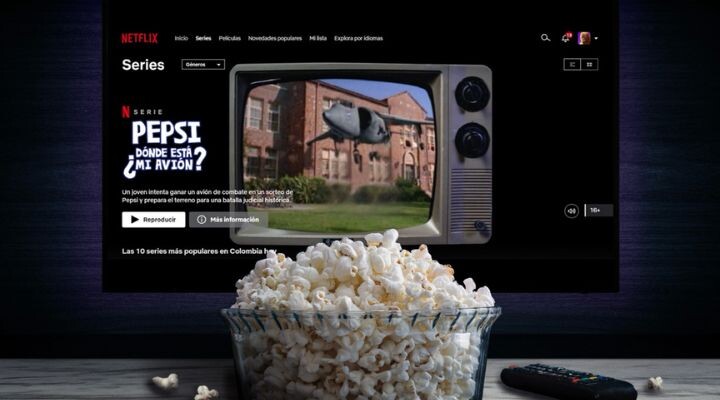 Un bol de palomitas y un control remoto se encuentran sobre una mesa frente a un televisor que muestra la serie de Netflix "PEPSI, ¿DÓNDE ESTÁ MI AVIÓN?", narrando una inolvidable crisis de marca con la imagen de un televisor antiguo.