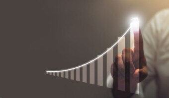 Una persona interactúa digitalmente con un gráfico de barras ascendente, que simboliza el crecimiento o progreso en el mercado de SaaS, resaltado con un brillo blanco sobre un fondo gris.