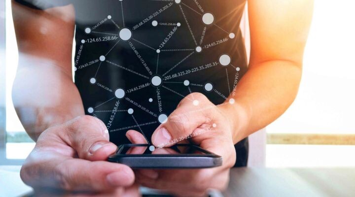 Una persona usa un teléfono inteligente con una superposición gráfica de red digital que muestra nodos conectados y direcciones IP, lo que ilustra cómo la tecnología móvil impulsa la estrategia de medios en un mundo interconectado.