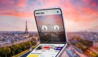 Un teléfono inteligente que muestra una aplicación de los Juegos Olímpicos de París 2024, con la Torre Eiffel y un paisaje urbano borroso de fondo.