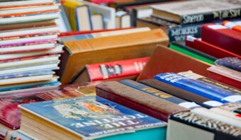 Una variedad de libros apilados y ordenados sobre una mesa, que se asemejan a un diseño editorial de marketing. Algunos se apilan horizontalmente, mientras que otros se colocan verticalmente. Los títulos y portadas son de diferentes colores.