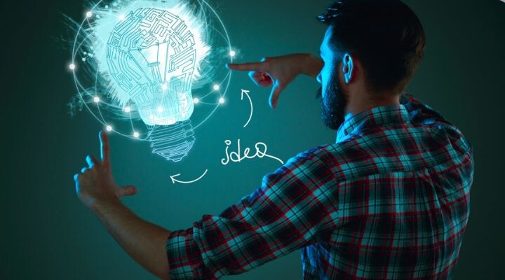 Un hombre con una camisa a cuadros hace un gesto hacia una bombilla digital brillante con la palabra "idea" y flechas dibujadas al lado, que simbolizan innovación, creatividad o lluvia de ideas.