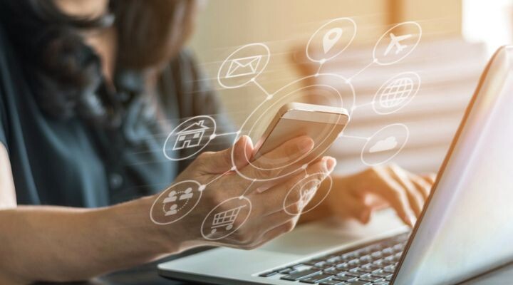 Una persona usa un teléfono inteligente y una computadora portátil, rodeada de íconos digitales que representan la innovación en varios servicios y aplicaciones en línea.