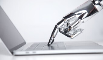 Una mano robótica tocando el teclado de una computadora portátil, sugiriendo interacción entre inteligencia artificial y tecnología.
