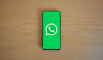 Teléfono inteligente sobre una superficie de madera que muestra el logotipo de WhatsApp Business en su pantalla.