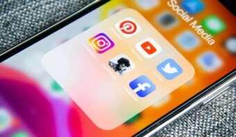 Pantalla de teléfono inteligente que muestra una carpeta denominada "Redes sociales" que contiene aplicaciones de Pinterest, YouTube, Instagram, Twitter y Facebook con publicidad sutil en la aplicación.