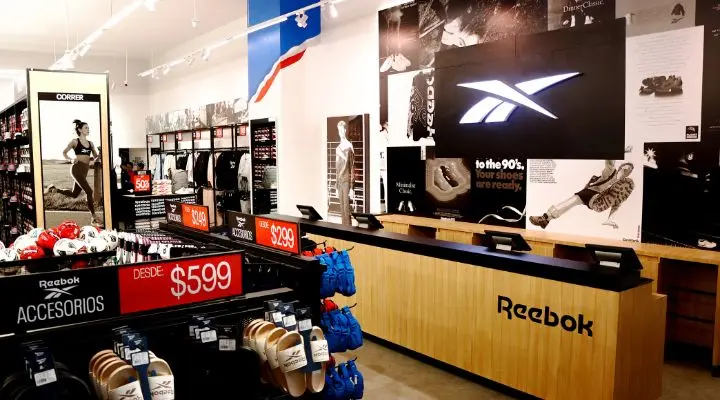 La tienda Outlet Puebla Premier Reebok exhibe ropa, zapatos y accesorios, con llamativos displays y señalización que resaltan productos y precios.