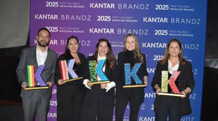 Cinco personas sostienen premios coloridos con la letra "K" frente a una pancarta de Kantar BrandZ.
