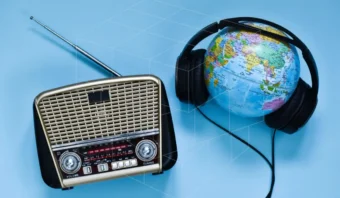 Radio vintage y globo terráqueo con auriculares sobre fondo azul.