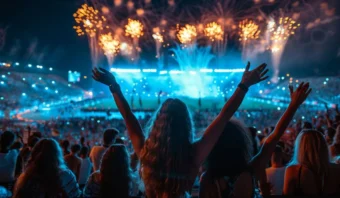 Una multitud disfruta de un vibrante espectáculo de fuegos artificiales sobre un estadio por la noche, con luces de colores que iluminan la escena.
