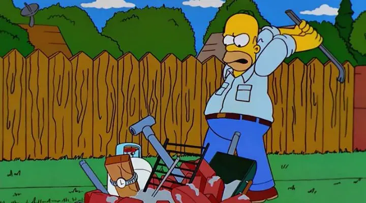 Homero Simpson, experimentando el Efecto IKEA, golpea enojado con una palanca una parrilla improvisada en un patio trasero.