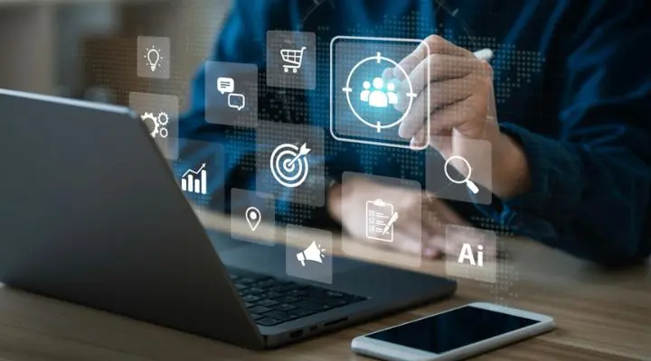Una persona usa una computadora portátil, interactuando sin problemas con íconos digitales como un carrito de compras, un objetivo y una IA, todo para seleccionar medios de manera experta para mejorar su experiencia en línea.