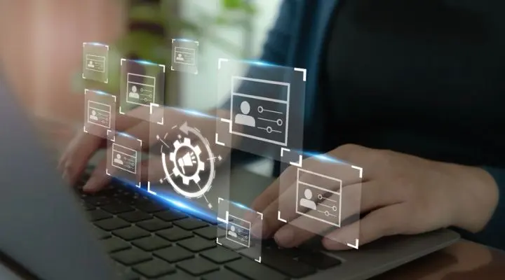 Manos escribiendo en una computadora portátil con hologramas digitales flotantes que muestran íconos y configuraciones alrededor de la pantalla, integrando perfectamente herramientas de planificación de medios para optimizar el flujo de trabajo.