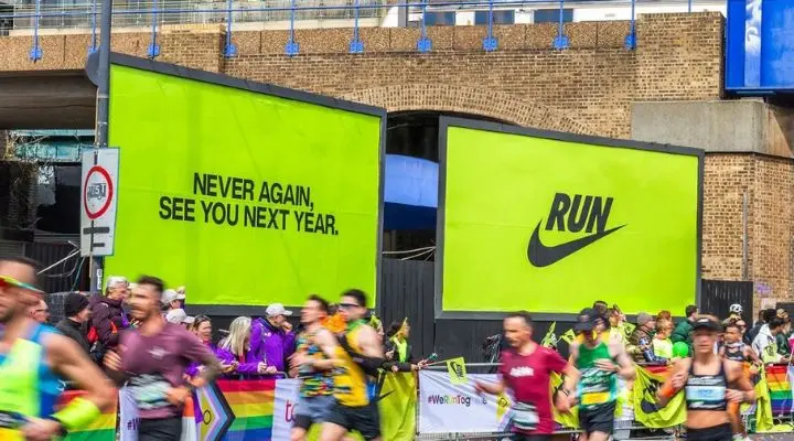 Los corredores pasan junto a dos grandes carteles publicitarios de Nike que refuerzan su reputación de marca: uno dice "NUNCA MÁS, NOS VEMOS EL AÑO QUE VIENE" y el otro muestra con valentía "CORRE".