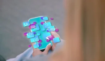 Persona que sostiene un teléfono inteligente con íconos digitales flotantes y símbolos de aplicaciones proyectados sobre la pantalla, lo que sugiere realidad aumentada o una interfaz digital.