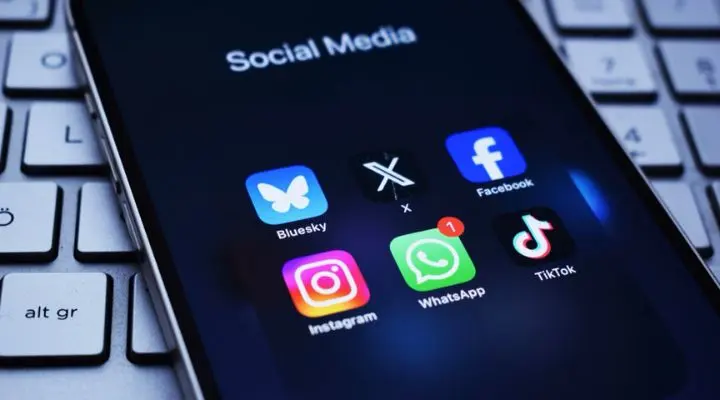 Un teléfono inteligente muestra íconos de aplicaciones de redes sociales, incluidas Bluesky, X, Facebook, Instagram, WhatsApp y TikTok (plataformas clave para la compra de medios), colocados en un teclado de computadora.