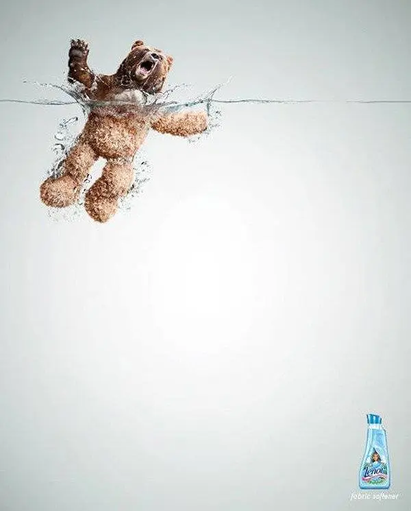 Un osito de peluche flota sobre el agua con aspecto alarmado, con una botella de suavizante de telas en la esquina inferior derecha: un ejemplo perfecto de anuncios creativos.