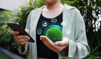 Una persona sostiene una bola de musgo verde y un teléfono inteligente, con íconos de sustentabilidad, ecología y atención al cliente superpuestos digitalmente sobre el musgo mostrando la atención al cliente